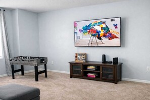 Ein Zimmer mit einem Kicker, einem Bücherregal und einem farbenfrohen Bild an der Wand.