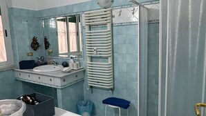 Un baño con lavadora, lavamanos, espejo, toallero y cabina de ducha.