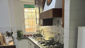 Una cocina con estufa a gas, lavaplatos y horno, armarios de madera y una ventana con vistas.