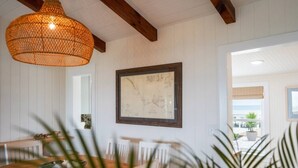 Een eetgedeelte met een houten tafel, stoelen, een hanglamp en een lijst met een kaart aan de muur.