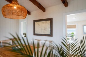 Ein Essbereich mit Holztisch, Stühlen, einer Pendelleuchte und einer gerahmten Karte an der Wand.