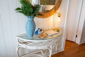 Ein Tisch mit Glasplatte, eine blaue Vase, eine Lampe und ein Buch.