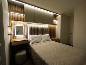 Een hotelkamer met een bed, nachtkastjes, een spiegel en een kledingkast.