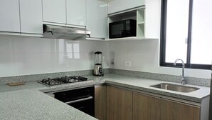 A kitchen with white cabinets, a gas stove, a microwave, and a blender.
