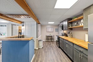Une cuisine moderne avec des plans de travail en bois, des placards intégrés et un coin repas comprenant une table et des chaises.