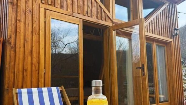 A wooden cabin with a dining area featuring a table, chairs, and a bottle. - Wilgano (Rvaši)