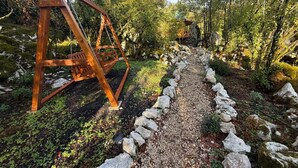 A wooden swing set in a forested area with a gravel path and rocks. - Wilgano (Rvaši)