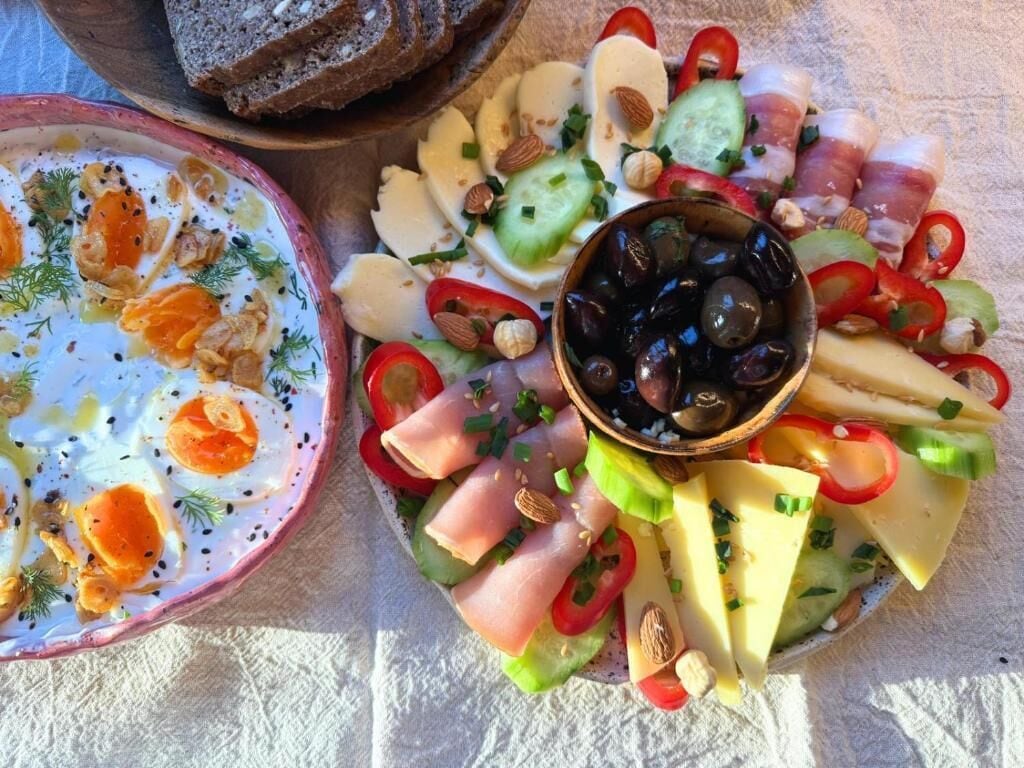A platter with various cheeses, cured meats, olives, and vegetables.