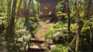 A cabin surrounded by trees, with a wooden deck and a chair. - Wilgano (Rvaši)