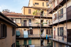 A multi-story residential building with balconies, air conditioning units, and potted plants. - Procaccini, 54 – Urban Stay Sempione–Sarpi (Milano)