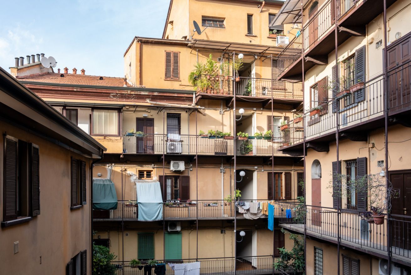 A multi-story residential building with balconies, air conditioning units, and potted plants.