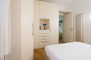 A bedroom with a bed, a wardrobe, and a small shelf with a vase. - Procaccini, 54 – Urban Stay Sempione–Sarpi (Milano)
