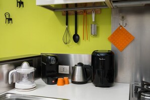 A kitchen with a juicer, coffee maker, kettle, and orange cups on the counter. - Procaccini, 54 – Urban Stay Sempione–Sarpi (Milano)