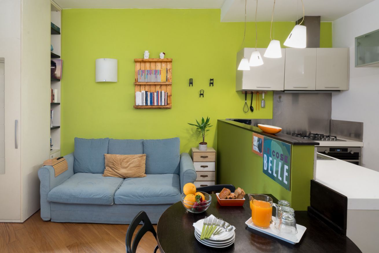 A modern living space with a sofa, dining table, and kitchen area.