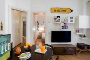 A modern living room with a dining area, a flat-screen TV, and a sign that reads 'deviazione.' - Procaccini, 54 – Urban Stay Sempione–Sarpi (Milano)