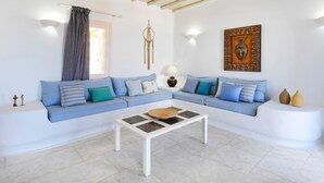 Ein stilvolles Wohnzimmer mit einem blauen Sofa, einem weißen Couchtisch und einer dekorativen Wandarbeit.
