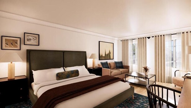 A hotel room with a bed, a sofa, a small table, and a chair.