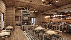A log cabin interior with round tables, chairs, a fireplace, and a bar area.
