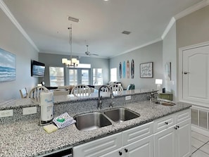 A modern kitchen with granite countertops, stainless steel sinks, and white cabinetry. - Seascape Golf Villas 407 (Miramar Beach)