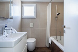 Une salle de bain avec une baignoire, des toilettes et une fenêtre.