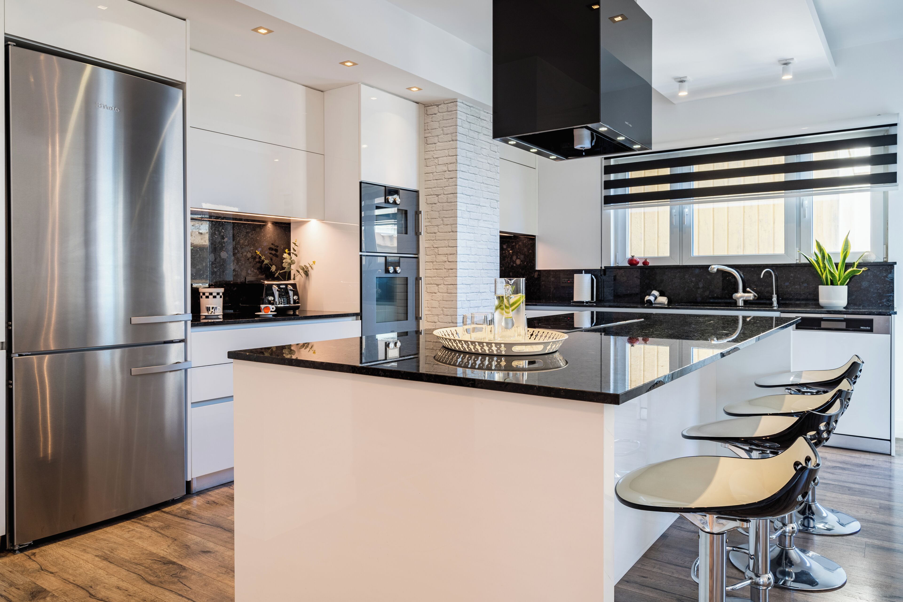 Uma cozinha moderna com eletrodomésticos de aço inoxidável, uma ilha central e banquetas.