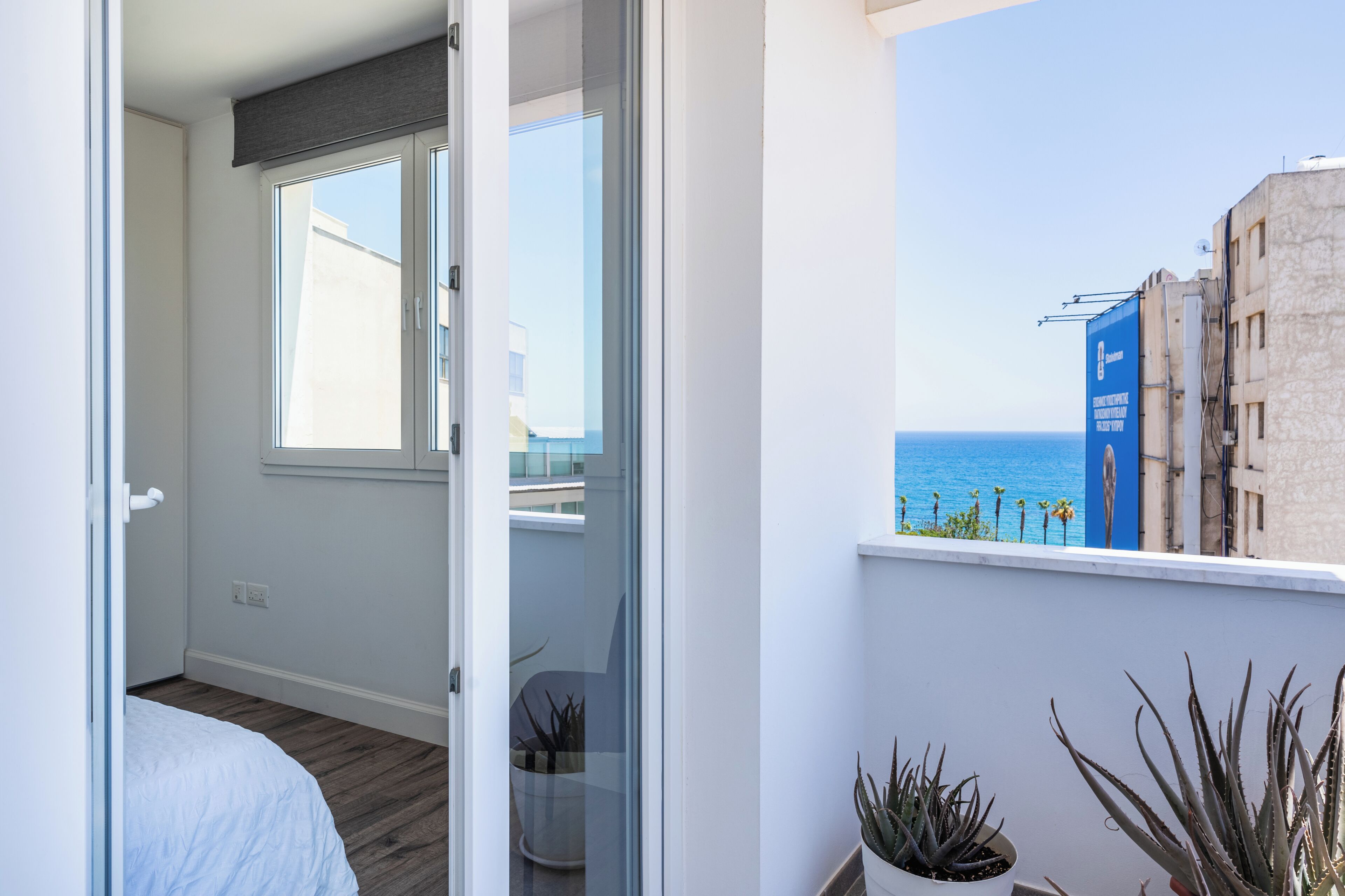 Uma varanda com vista para o mar, uma cama e plantas em vasos.