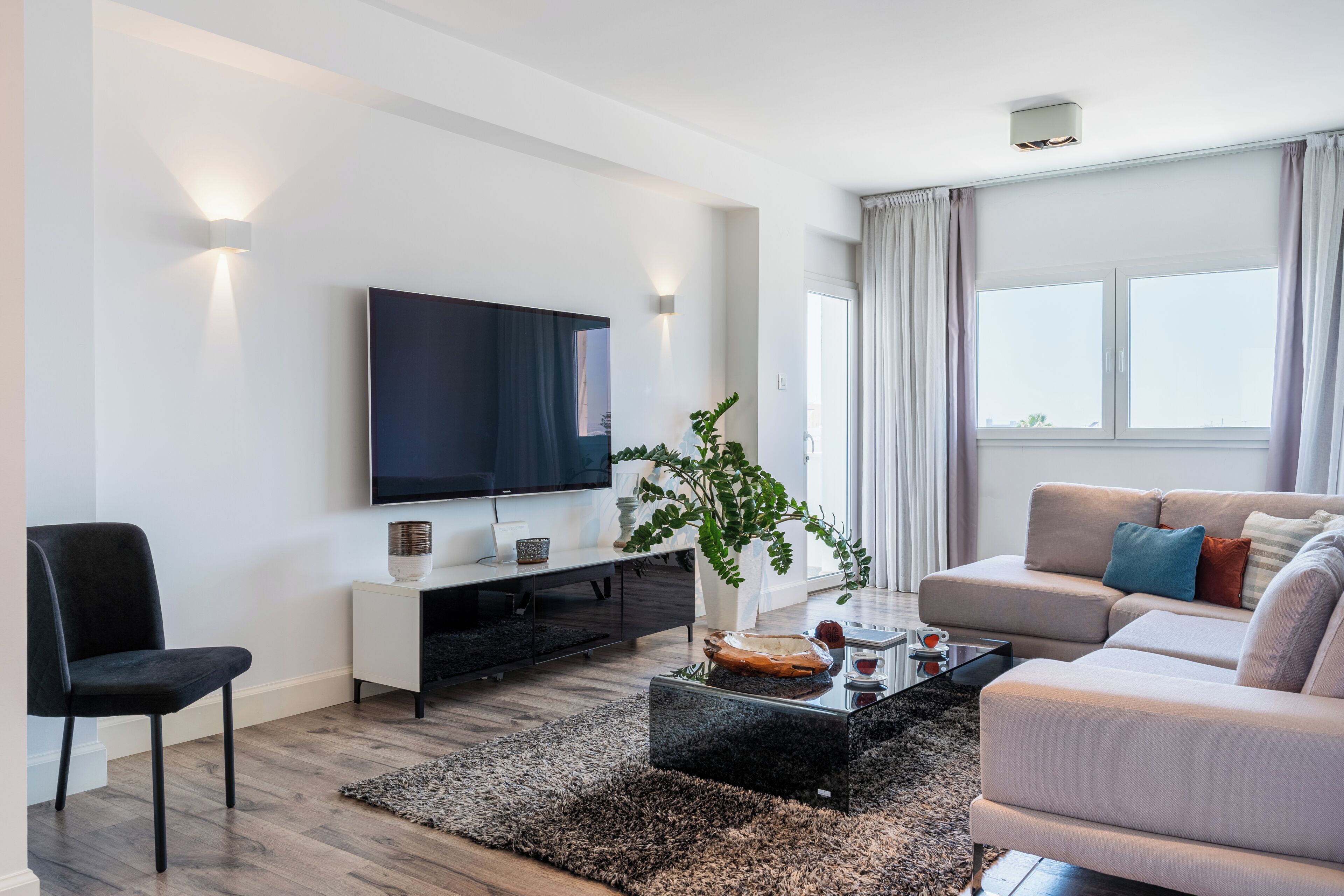 Uma sala de estar moderna com televisão de tela plana, um sofá, uma mesa de centro e uma planta.