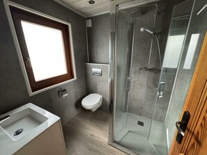 Een moderne badkamer met douche, toilet en wastafel.