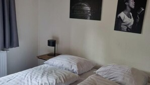 A room with two single beds, a small bedside table with a lamp, and two framed pictures on the wall. - Boekhorst Royal 6 (Susteren)