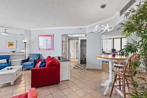 Ein modernes Wohnzimmer mit einem roten Sofa, einem blauen Sessel und einem Essbereich mit einem Holztisch und Stühlen.