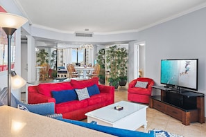 A spacious living room with a red sofa, a white coffee table, and a flat-screen TV. - Surfside Resort #604 (Miramar Beach)
