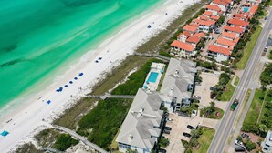 Vista aérea de una zona residencial costera con playa, piscina y una carretera.