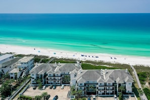 Ein Strandhotel mit mehreren Gebäuden, einem Parkplatz und Blick auf den Ozean und den Strand.