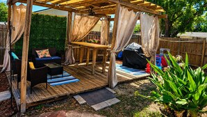 Eine Holzterrasse mit einer Pergola, Gartenmöbeln und einem kleinen Tisch.