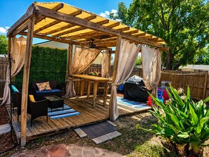 A wooden deck with a pergola, outdoor furniture, and a small table. - Hidden Oasis - Pool & Gameroom Close to Downtown, Theme Parks & Springs (Orlando)