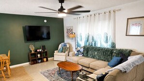 Ein Wohnzimmer mit Sofa, Couchtisch, Fernseher und Deckenventilator.