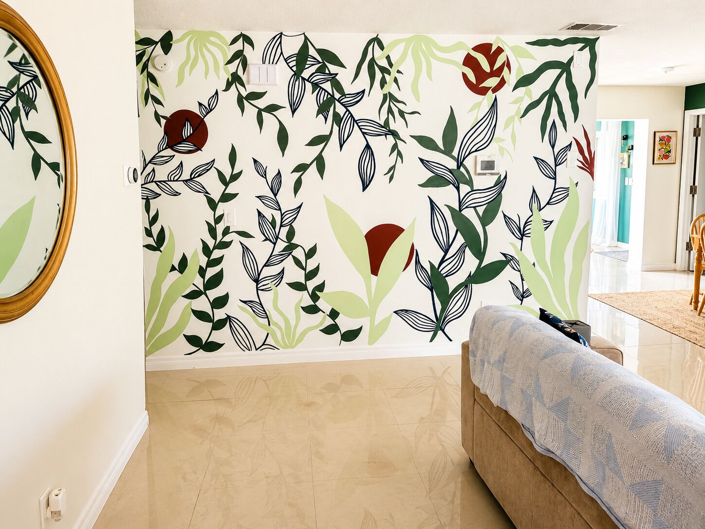 Ein Zimmer mit einem gemusterten Wand, Holzboden, einer Couch und einem Spiegel.