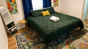 Ein Schlafzimmer mit einem Bett, einem Spiegel, einem kleinen runden Tisch und einem gemusterten Teppich.
