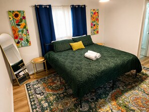 A bedroom with a bed, a mirror, a small round table, and a patterned rug. - Hidden Oasis - Pool & Gameroom Close to Downtown, Theme Parks & Springs (Orlando)