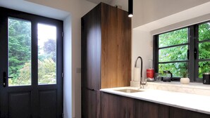Una cocina moderna con un armario de madera oscura, encimera blanca, lavaplatos empotrado y ventana con vistas a zonas verdes.
