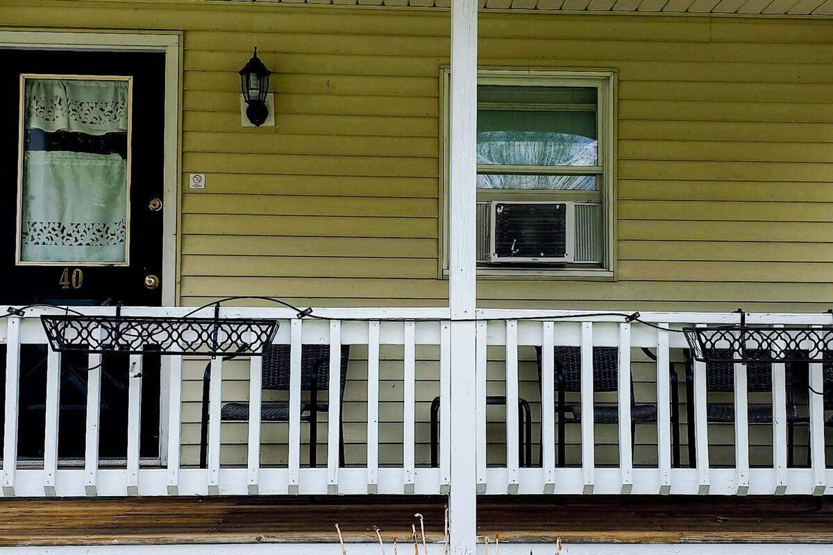 A house with a porch, a black door with a number, and a window with a curtain.