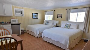 Quarto com duas camas, uma kitchenette pequena e um espaço para refeições.