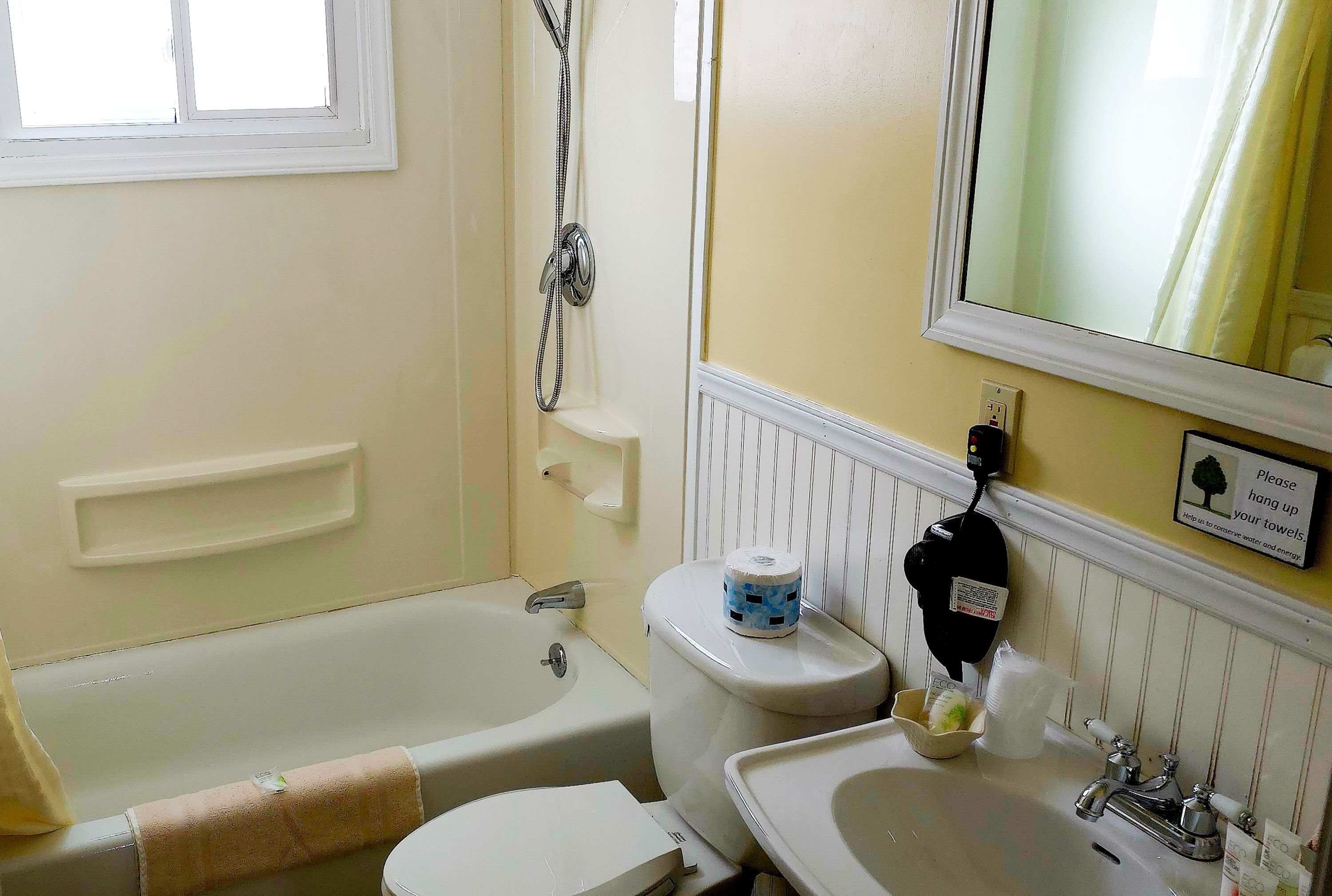 Un baño con bañera, inodoro, lavamanos y espejo.