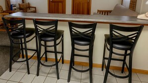 A kitchen with a bar area, wooden doors, and black bar stools. - Wilson Lake Inn & Suites (Wilton)