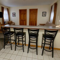 Una cocina con barra, puertas de madera y taburetes de bar negros.