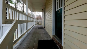 A covered wooden porch with a white railing, a door with the number 34, and a black doormat. - Wilson Lake Inn & Suites (Wilton)
