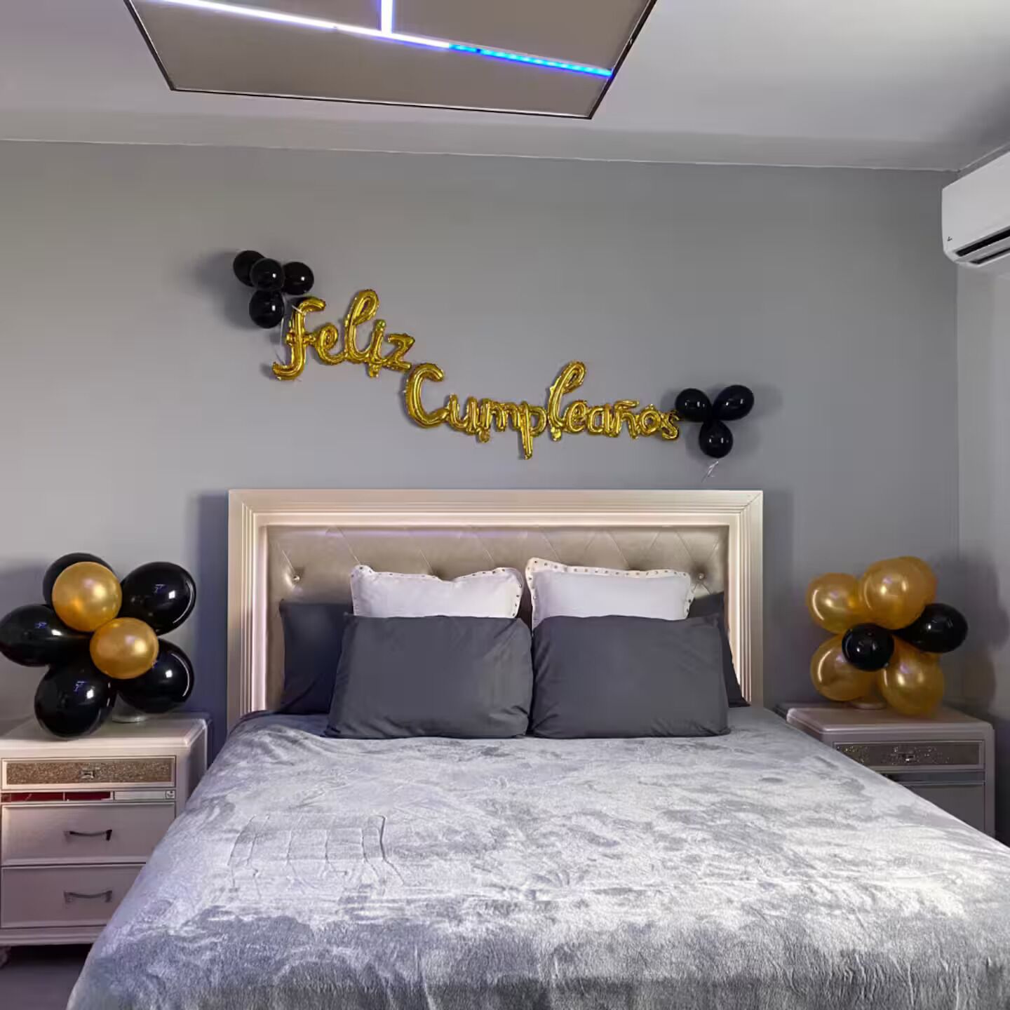 Un dormitorio con una cama, dos mesitas de noche, una decoración en la pared y una lámpara en el techo.
