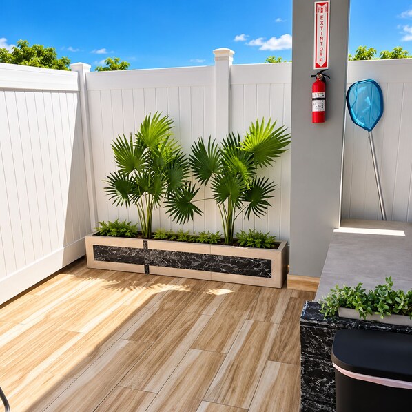 A patio with a white fence, a fire extinguisher, and a blue balloon.
