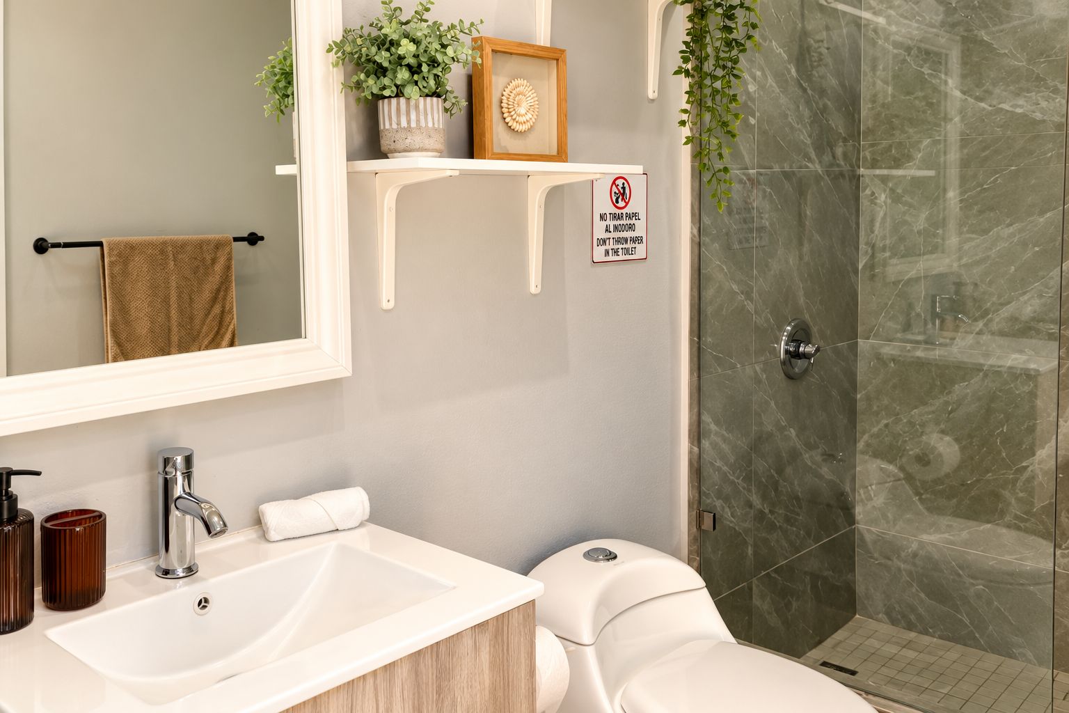 A modern bathroom with a white sink, a toilet, a shower with a glass door, and a towel rack.