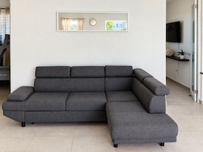 Un sofá seccional gris en una sala de estar moderna con un televisor de pantalla plana montado en la pared.